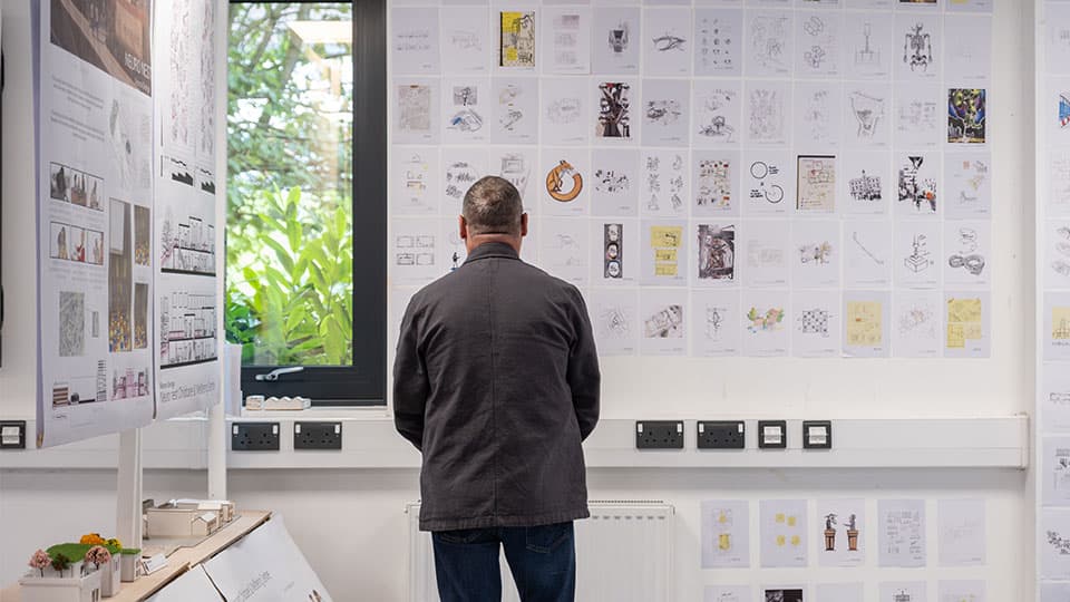 A man with his back to the camera looking at a display on a wall